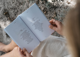 A woman reading a poetry book with poems and illustrations of a wave